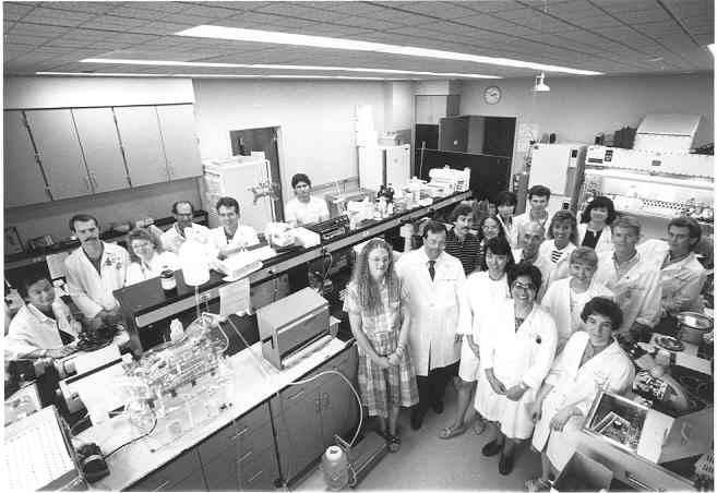 A group of people in lab coats stand together in a lab.