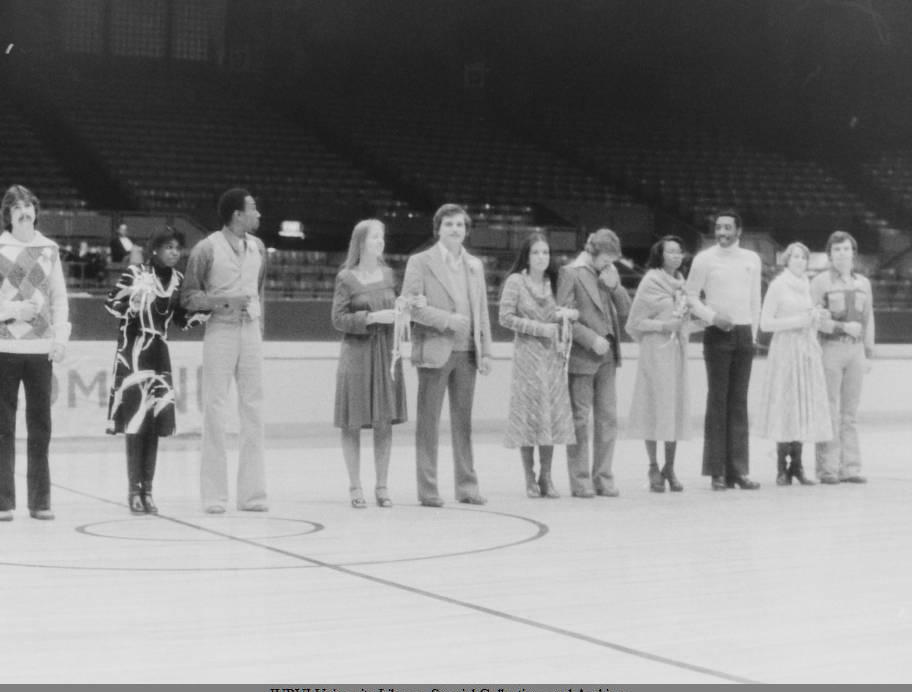 A group of people line up in a row in the middle of a basketball court.