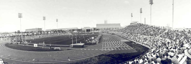 A view of a running track from the stands. The stands are filled with people.
