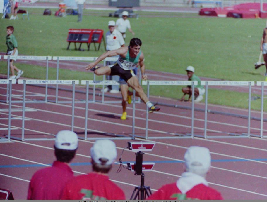 An athlete jumps over hurdles on a running track.