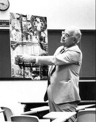 A man stands holding a layout on poster board showing a develop map of downtown Indianapolis