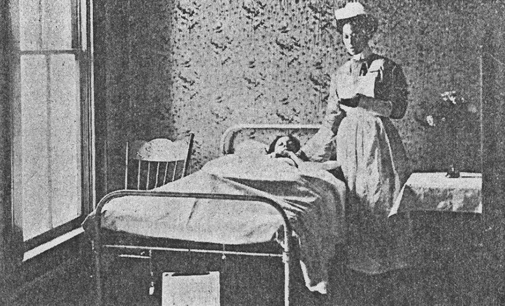 A nurse stands next to a patient in a hospital bed.