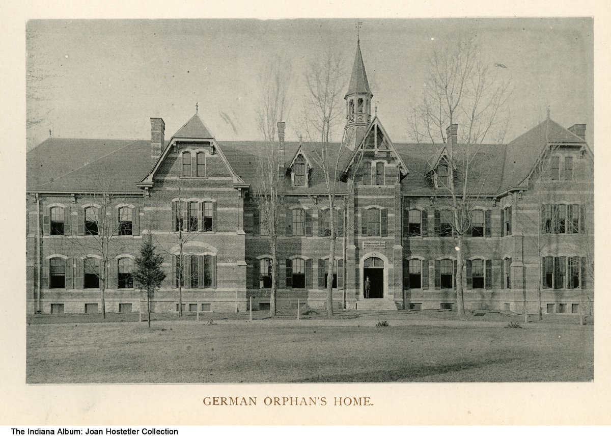 A long multistory brick building with a central spire.