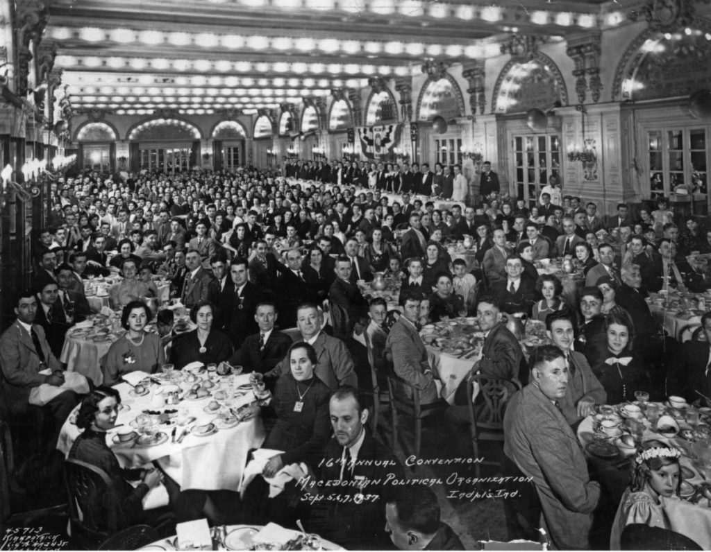 A large room crowded with people sitting at tables. 