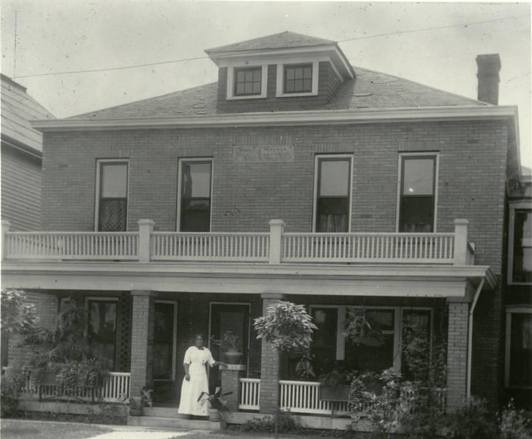 Madam Walker stands in front of her home and business.