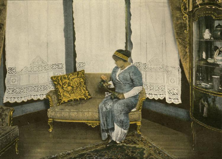 Madam Walker seated on a couch in front of a bay window at her home.
