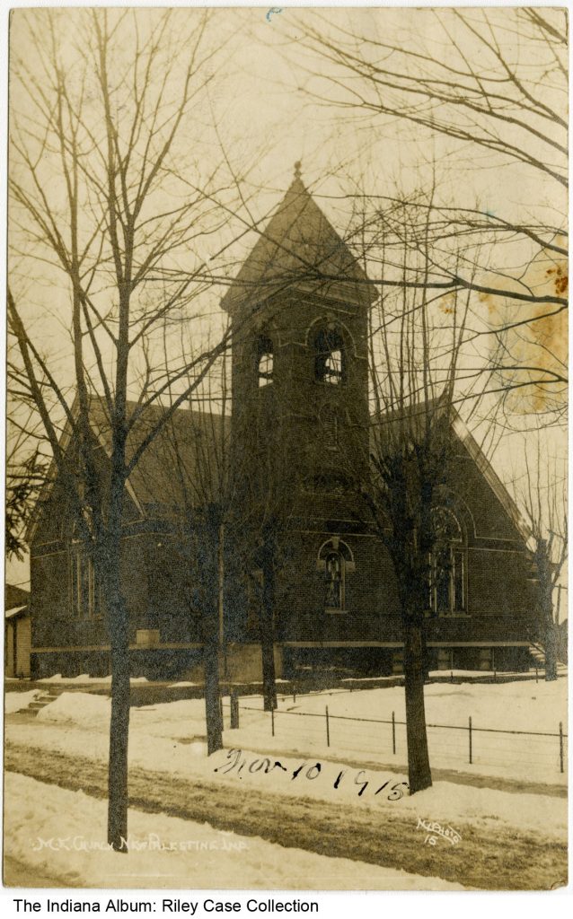 Exterior view of a church with a large bell tower off the side. 