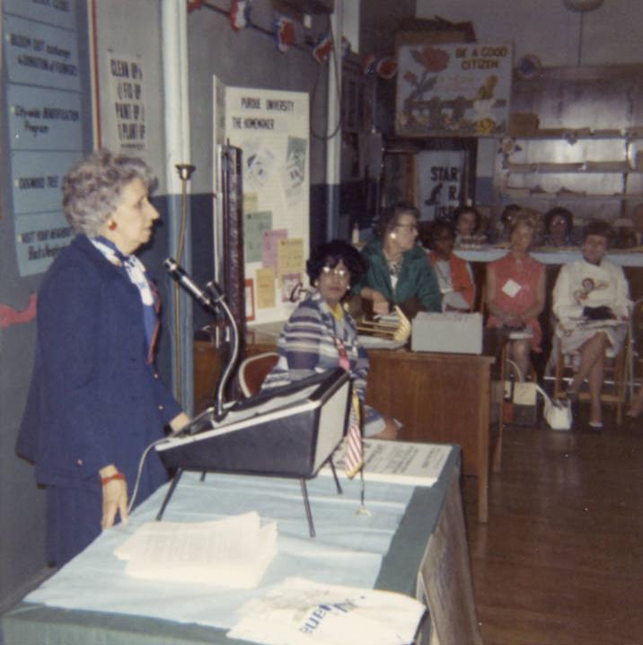 Margaret Moore stands and speaks into a microphone. 