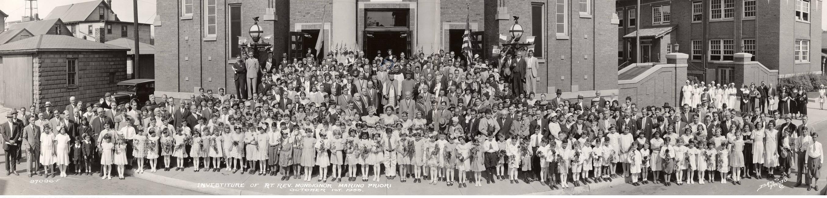 A large group of people gather outside a church for a group portrait.