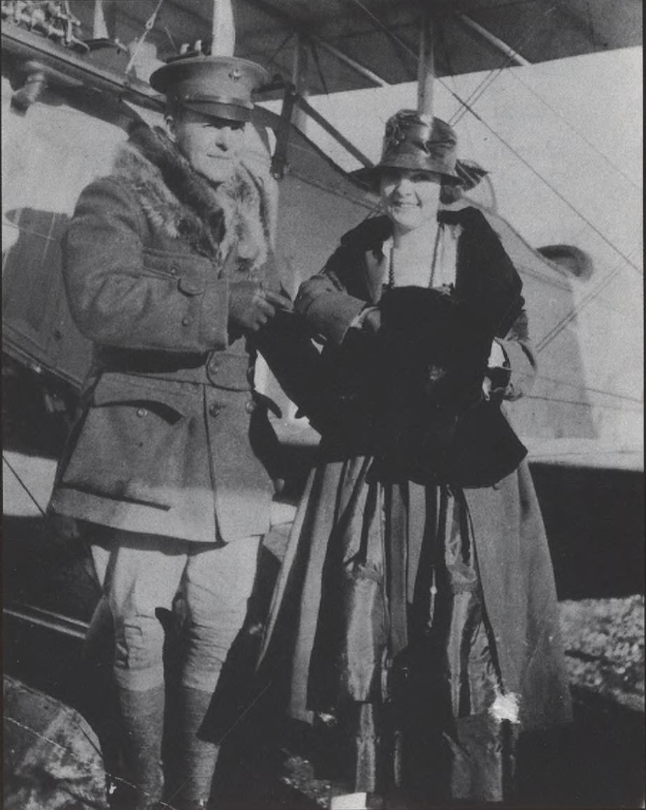 A man and woman stand in front of a small plane.