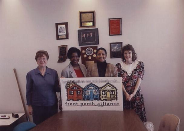A group of women stand behind a sign.