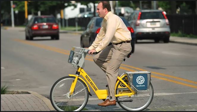 A man riding a yellow bicycle is crossing the street.