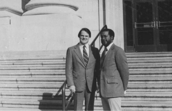 Two men stand on the steps leading to a building.