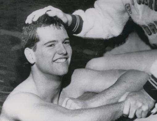A young man has his arms on the edge of a swimming pool.
