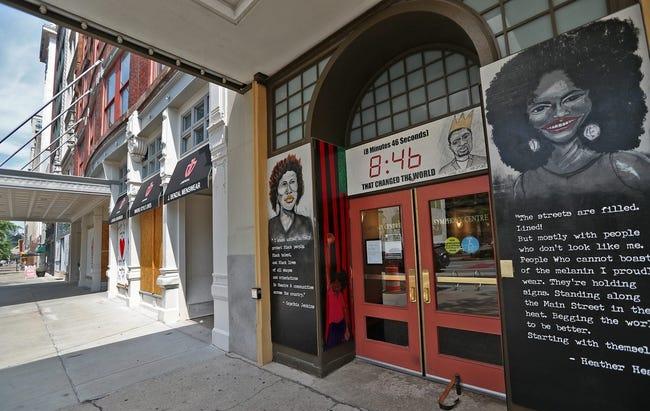 Two murals featuring likenesses of Black women flank either side of a set of double doors.