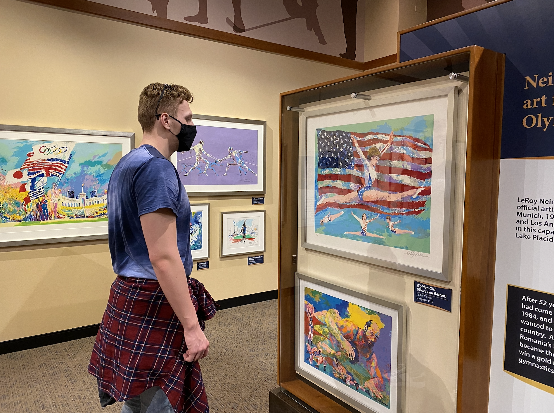 A visitor looks at a work of art depicting a gymnast in front of an American flag. 