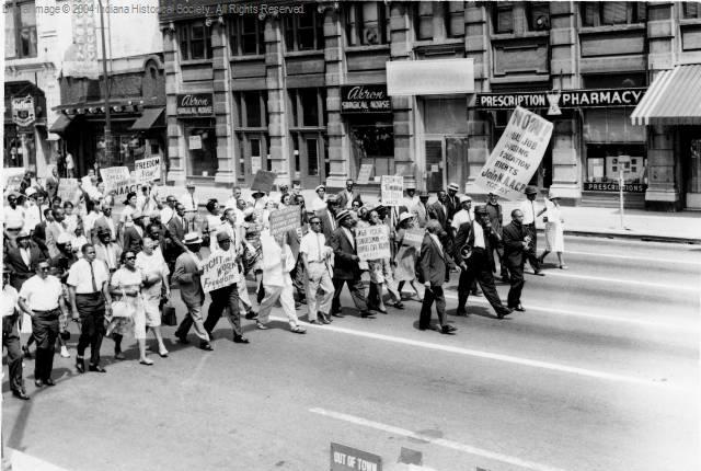 Activists are marching in the street carrying signs supporting the National Association for the Advancement of Colored People.