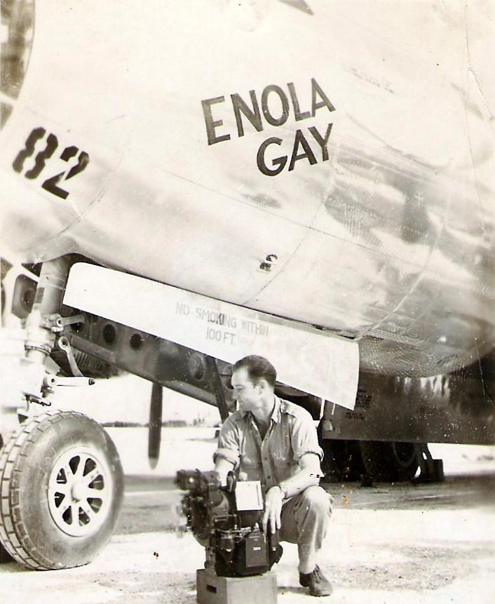 A man kneels in front of a plane.