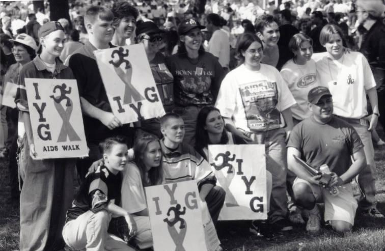 A group of young people pose. Some hold signs reading "IYG Aids Walk".