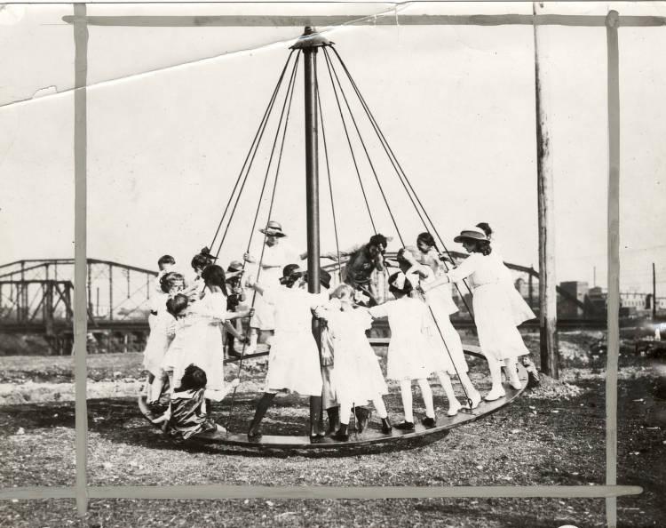 Children stand on a circular swing.