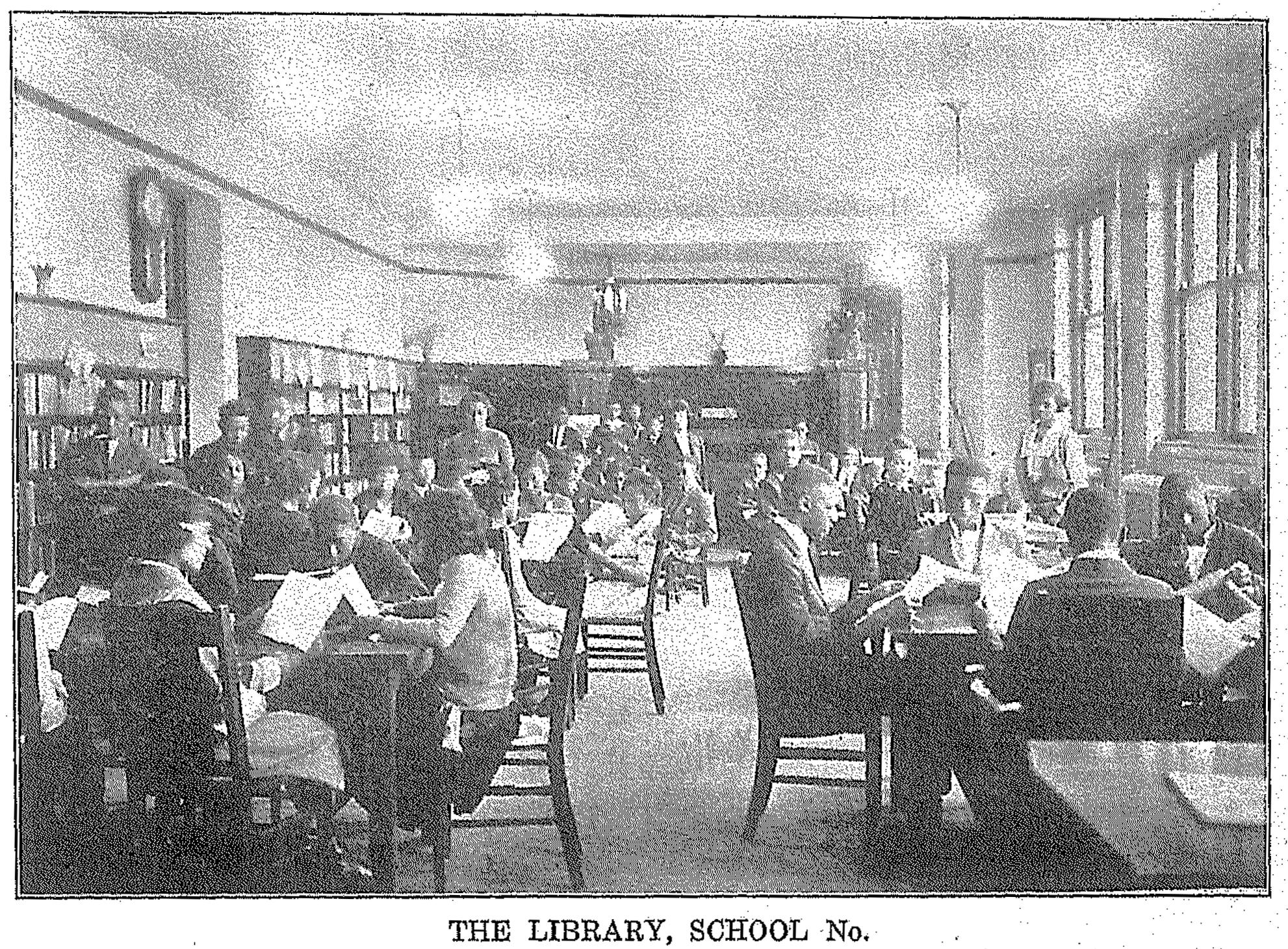 Students sit at tables in a large library.