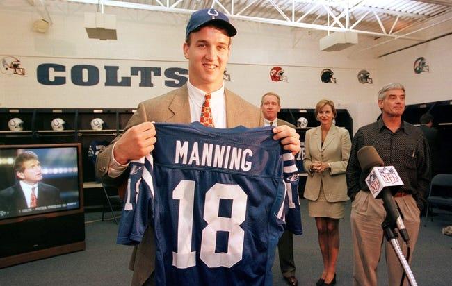 Peyton Manning holds up a jersey with his name and the number 18.