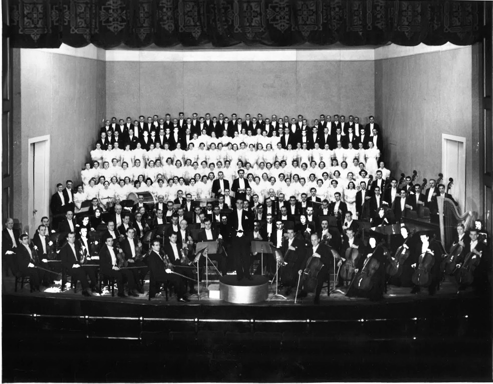 A stage is filled with an orchestra and a large choir. 
