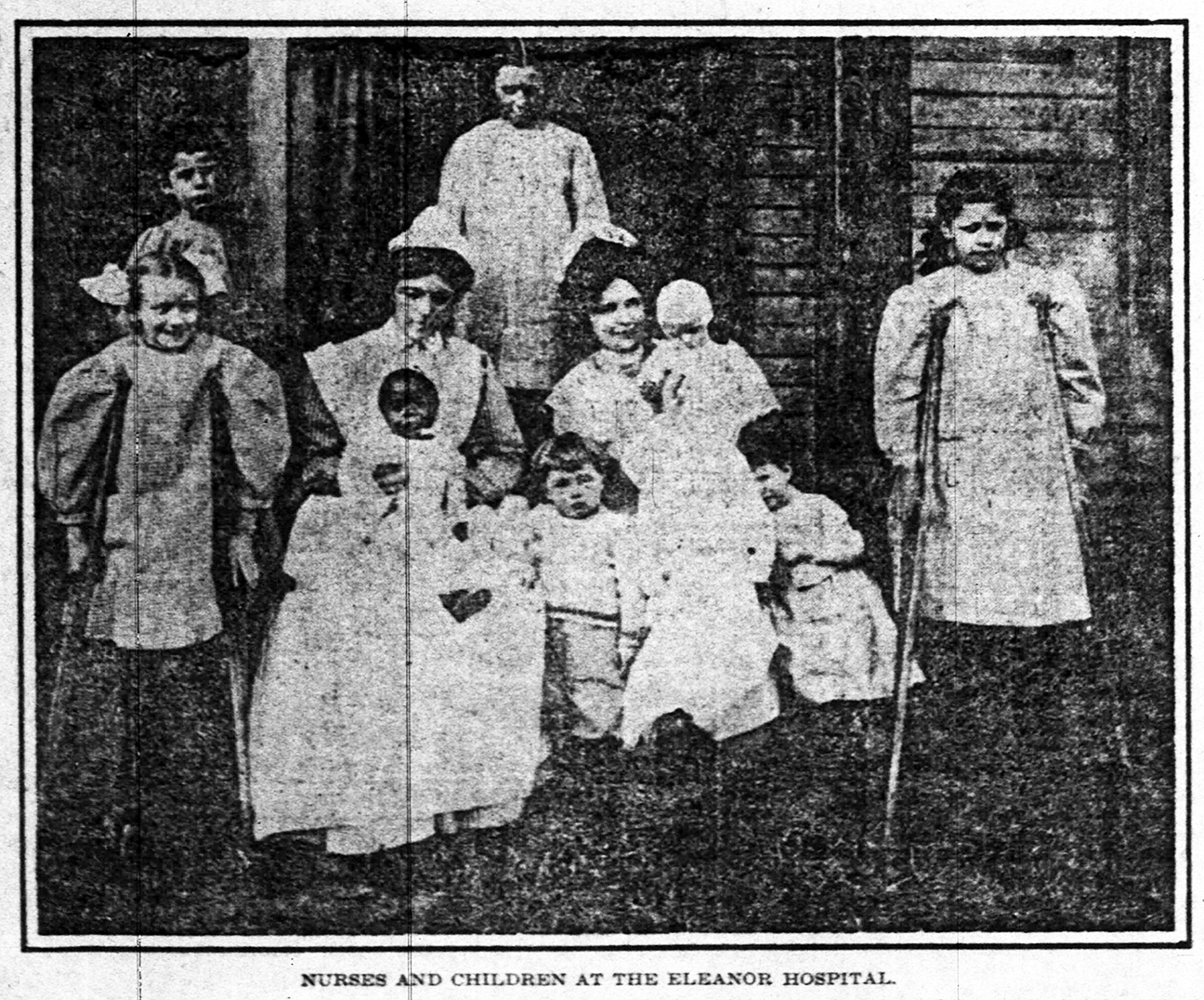 A newspaper clipping showing two women in aprons surrounded by several children of varying ages. 