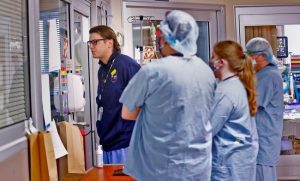 Medical personnel gather around the room of a patient at the Medical Intensive Care Unit at Roudebush VA Medical Center, 2020