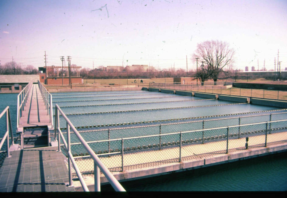 A walking bridge crosses over several holding tanks of water. 