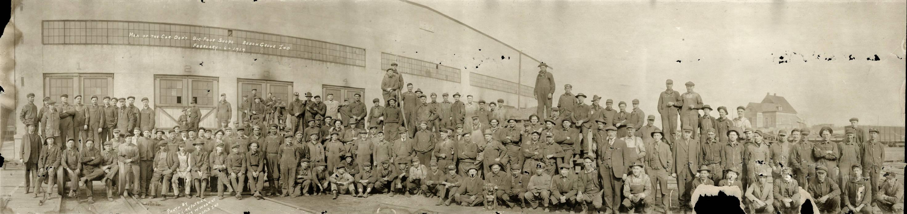 A large group of workers are gathered outside an industrial building. 