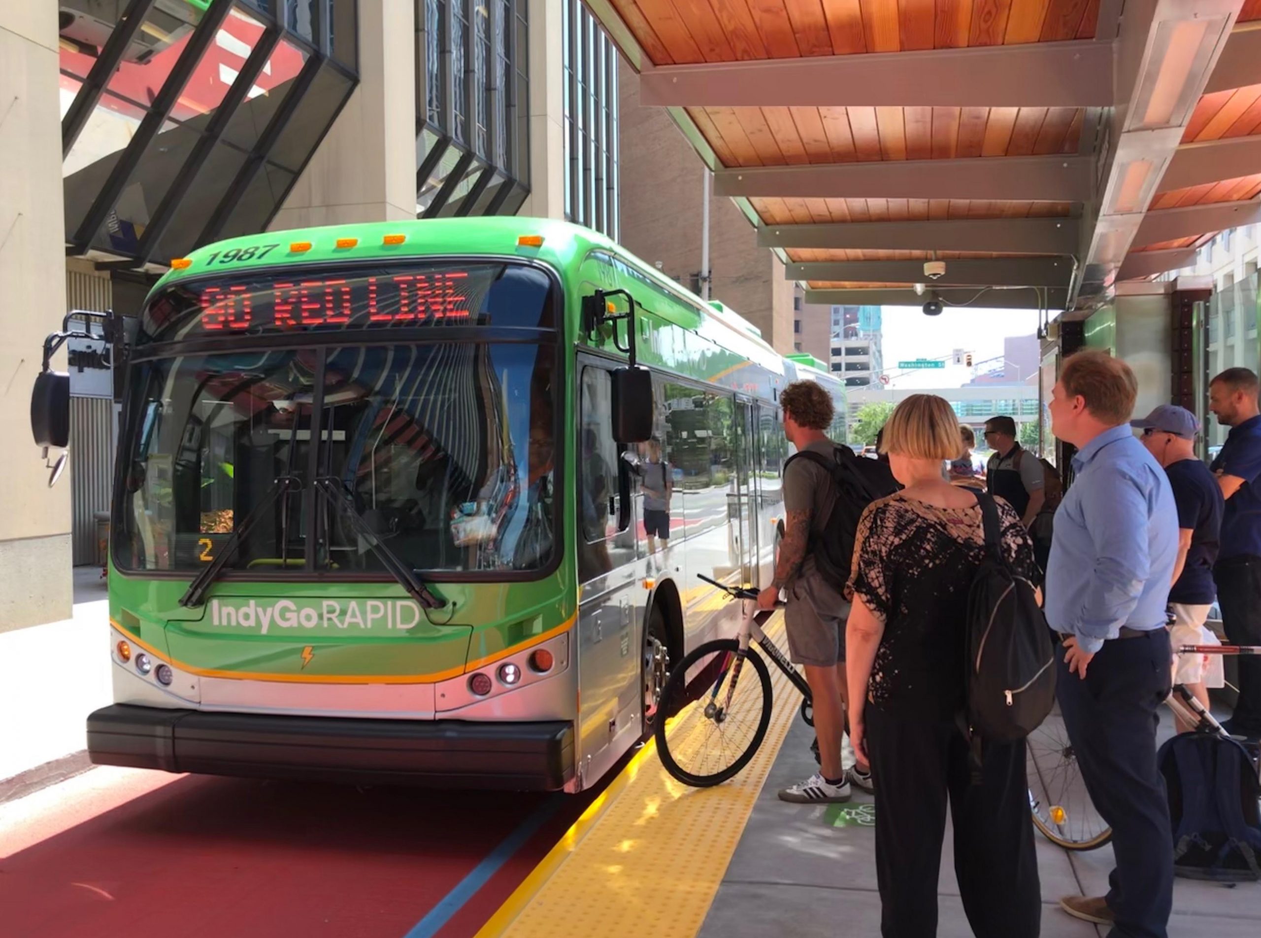 People wait on a platform as a bus pulls in next to it.