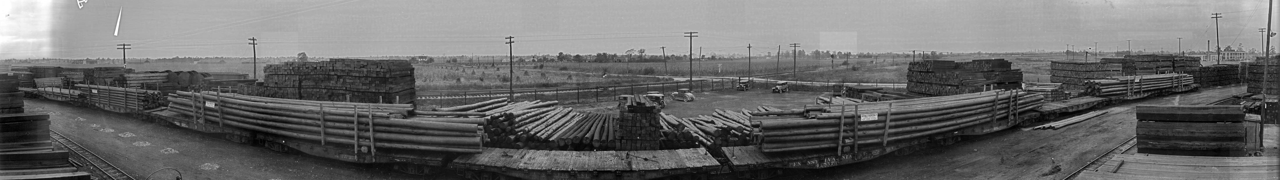 The plant operations along a railroad track with freight cars and stacks of lumber.