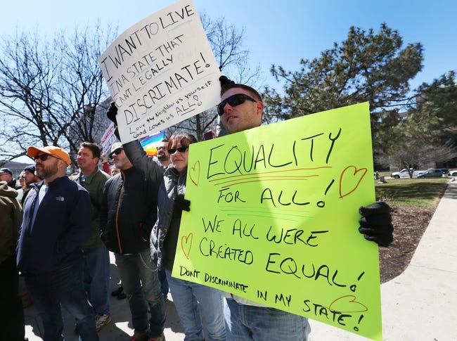 A group of protesters hold signs about equality.