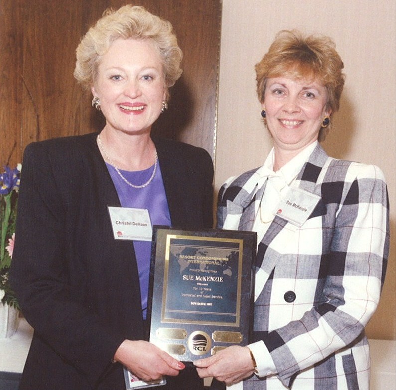 Two women pose together and hold a plaque. 