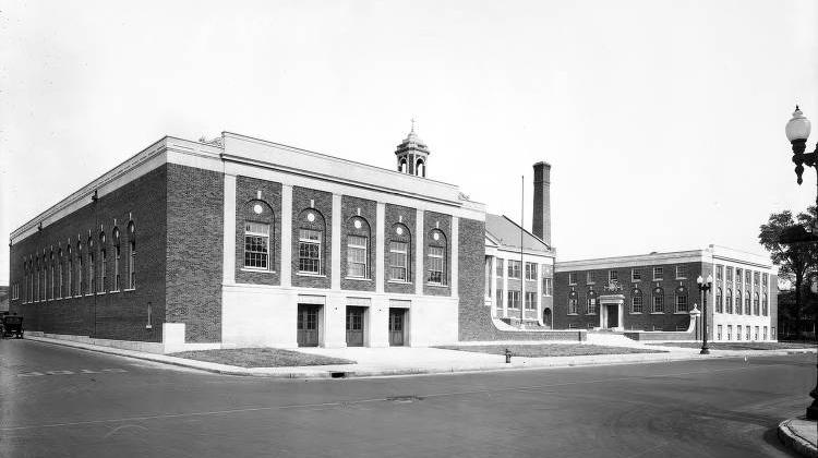 The large brick Federal style school has a central building with a large wing on each side. The central building has a cupola and a gabled entrance with columns.