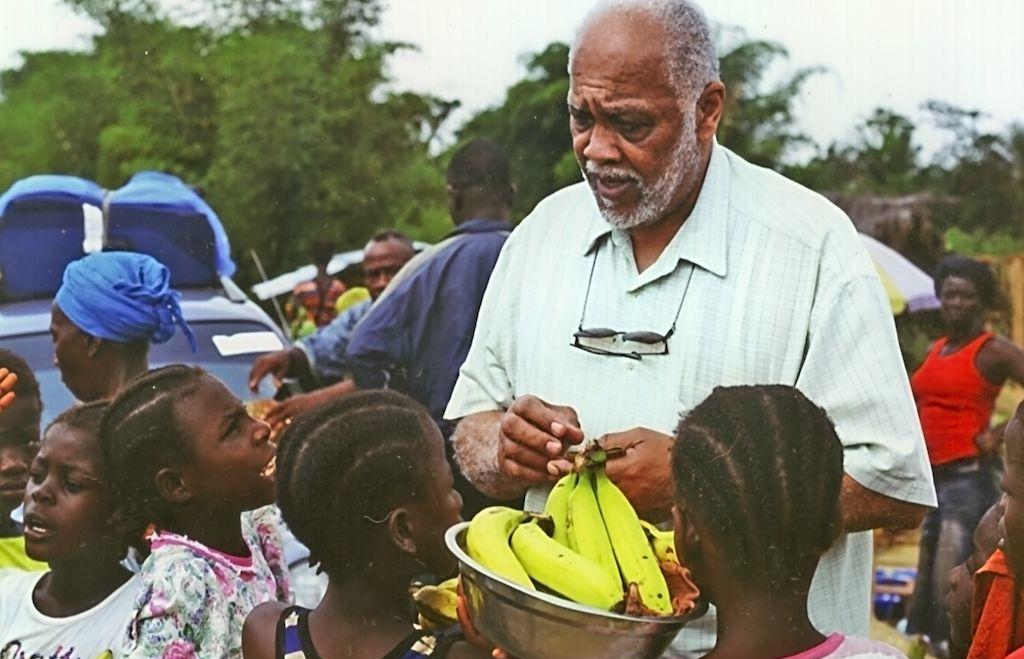 A man speaks to a group of children.