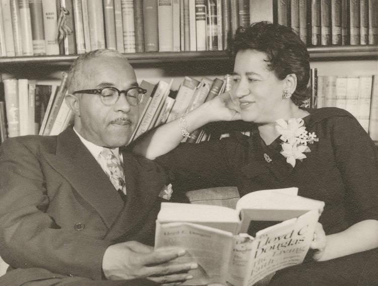 Henry Richardson Jr. and Roselyn Richardson sit on a couch and look at a book together.
