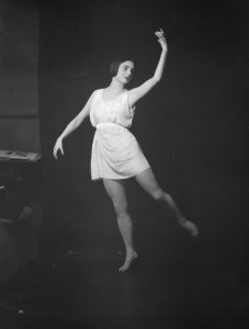 Ruth Page poses in a ballet move with one hand raised in the air.