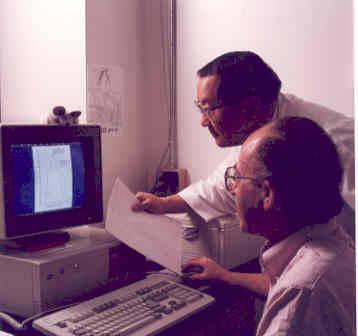 Two men look at a computer together.