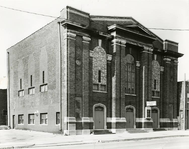 A multi-story brick building with three entrances in the front.