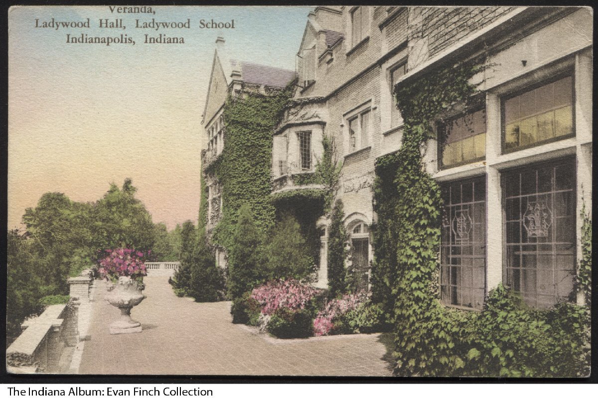 Postcard showing an ivy covered stone building and a large veranda.