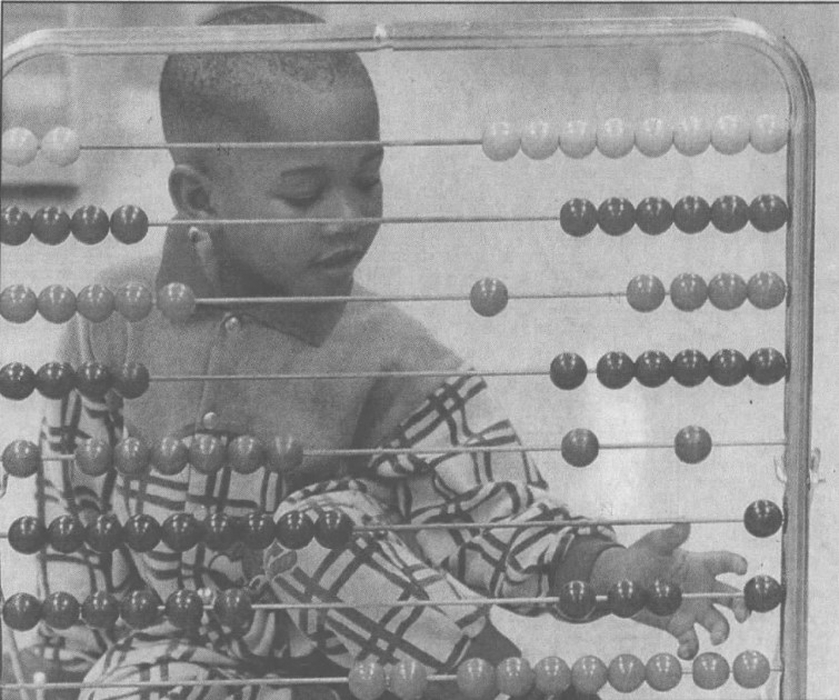 A young child plays with a toy abacus. 