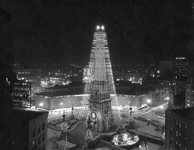 The monument is strung with rows of Christmas lights which creates a tree like look.
