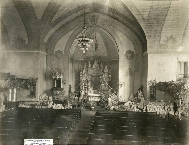 View of a church alter with rows of pews in the foreground. Food is gathered and arranged in the front of the church.