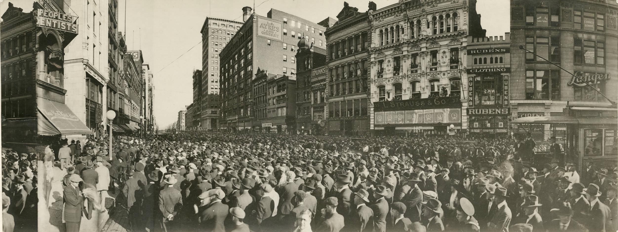 A large crowd of people completely fill a city street.