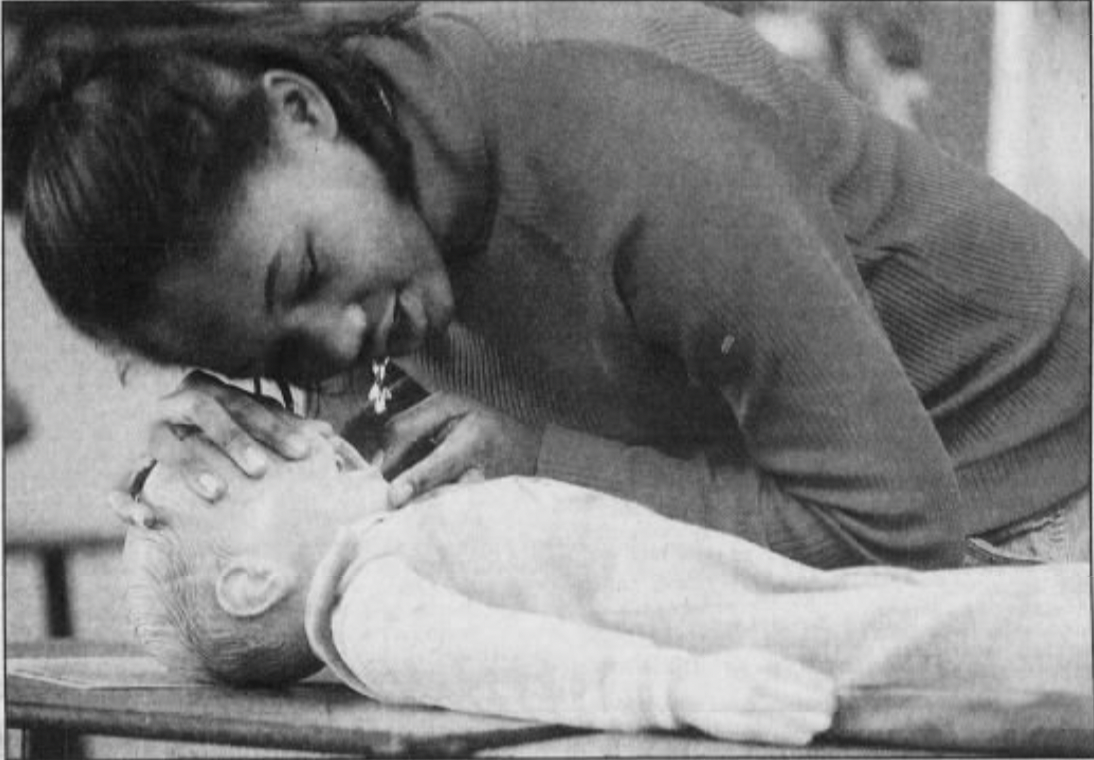 Teenage girl practicing CPR on a child-sized dummy as part of the Safe Sitter program.
