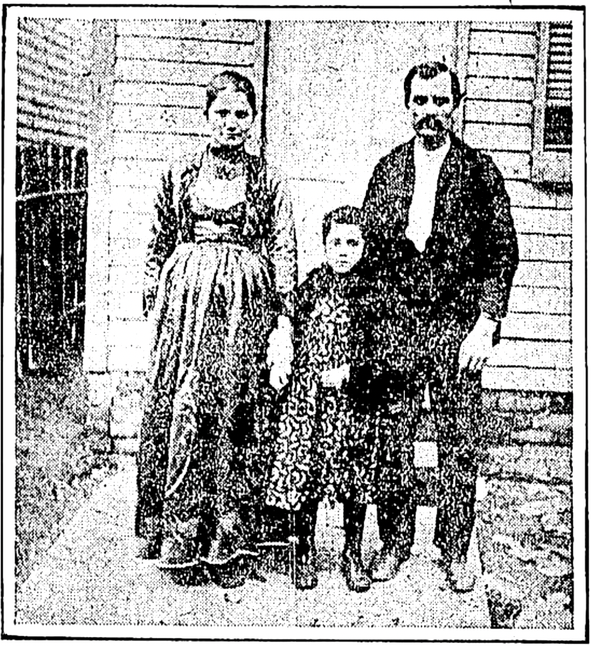 A man and woman stand with a young child in front of a house. 