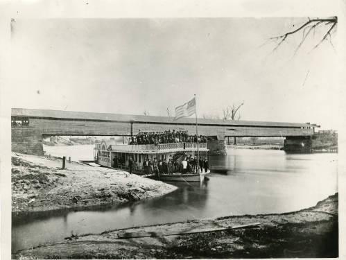 A steamboat filled with passengers is docked.