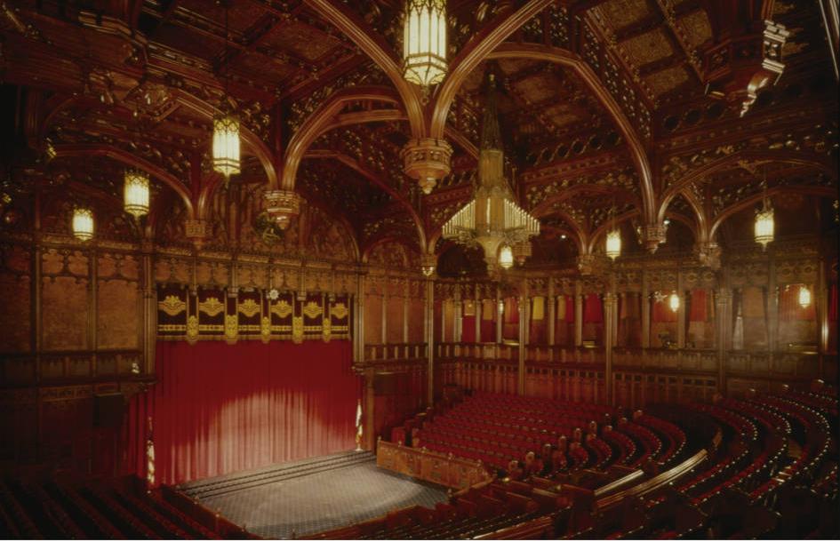 A large theater with curtains drawn over a central stage. 